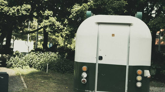 Empty food truck trailer parked under trees