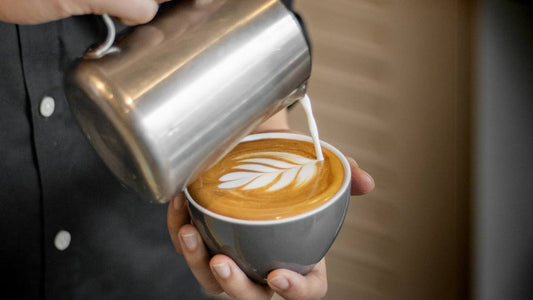 Barista pouring latte art into a cup