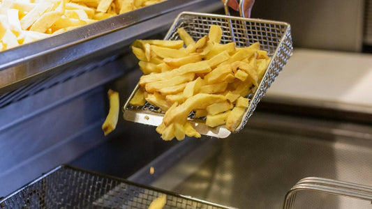 Chips being tipped into a commercial deep fryer basket