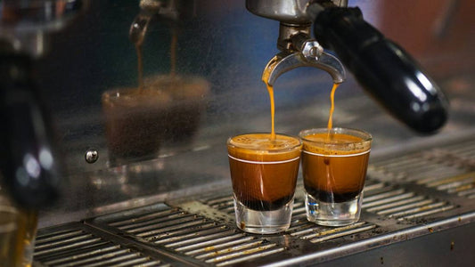 Two espresso shots pouring from a commercial machine